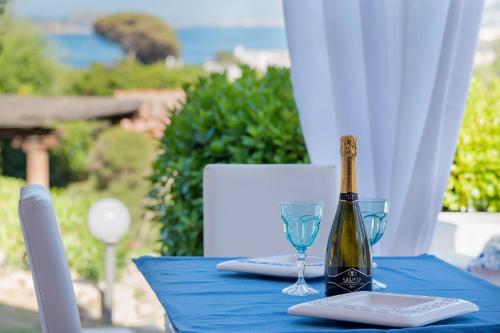 a blue table with a bottle of wine and glasses at Spectacular view of the Maddalena Islands in Porto Rafael