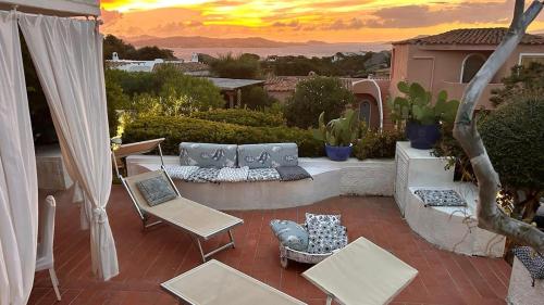 a patio with a couch and chairs and a sunset at Spectacular view of the Maddalena Islands in Porto Rafael