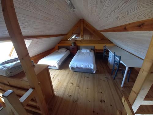 Cette chambre mansardée comprend deux lits, une table et des chaises. dans l'établissement longère spacieuse au calme, superbe vue mer, à Loc-Maria-Plouzané