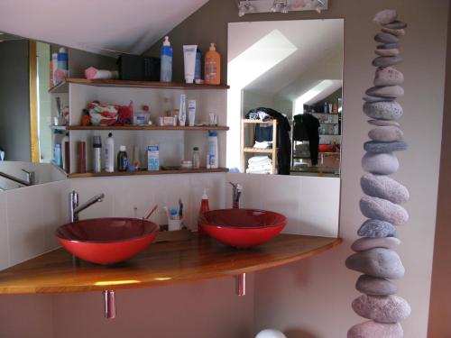 2 bols rouges sur une étagère dans une salle de bains dans l'établissement longère spacieuse au calme, superbe vue mer, à Loc-Maria-Plouzané