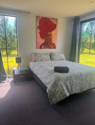 a bedroom with a bed and a painting on the wall at Lakin' it easy Cottage in Karapiro