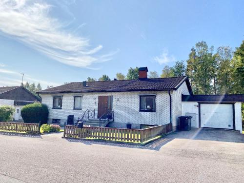 a white brick house with a gate and a garage at Ferienhaus mit Sauna nah zum Bade- und Angelsee in Skruv