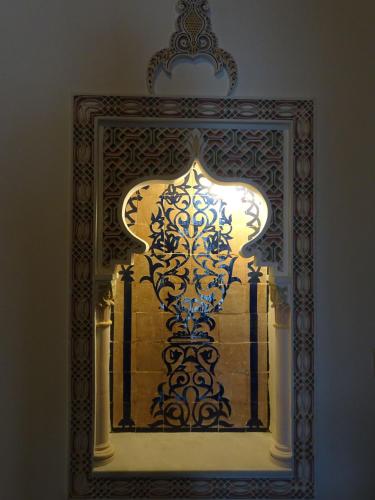 a mirror with a reflection of a vase on a wall at Riad Sabah in Fès