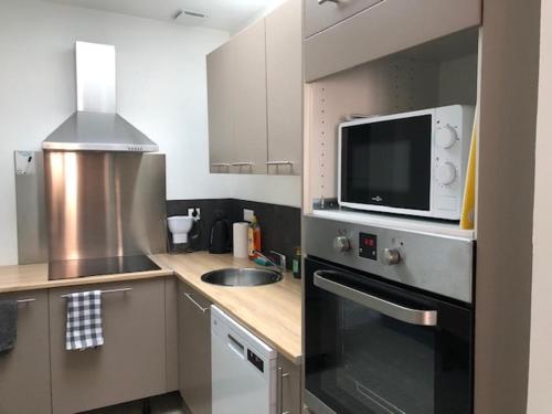 une cuisine avec un évier et un micro-ondes dans l'établissement La Canteraine, à Abbeville