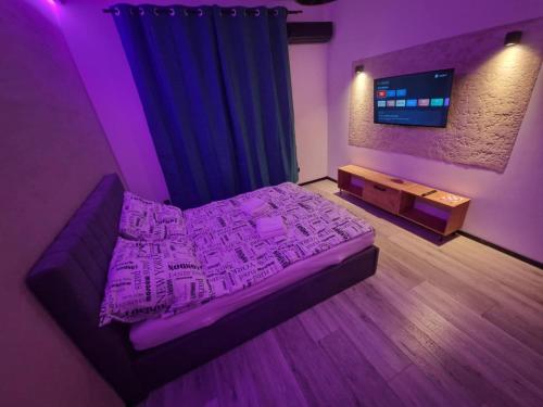 a purple bedroom with a bed and a tv at Apartament Zacisze 2 in Przemyśl