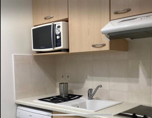 une cuisine avec un micro-ondes et un évier dans l'établissement appartement general Dumont, à La Rochelle
