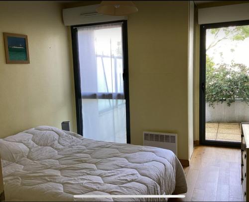 une chambre avec un lit et une grande fenêtre dans l'établissement appartement general Dumont, à La Rochelle