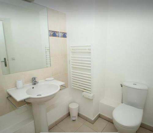 une salle de bain blanche avec des toilettes et un lavabo dans l'établissement appartement general Dumont, à La Rochelle