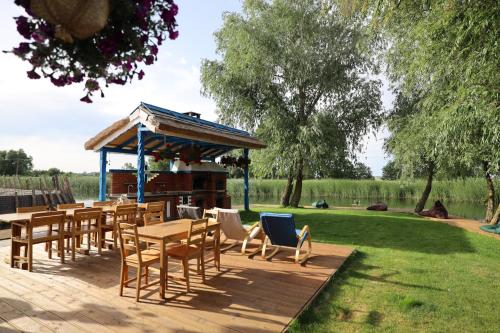 a wooden deck with tables and chairs and a gazebo at Casa Tasha in Dunavăţu de Jos