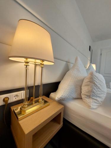 a lamp on a table next to a bed with pillows at Bodensee Sunshine Zimmer & Apts. in Uhldingen-Mühlhofen
