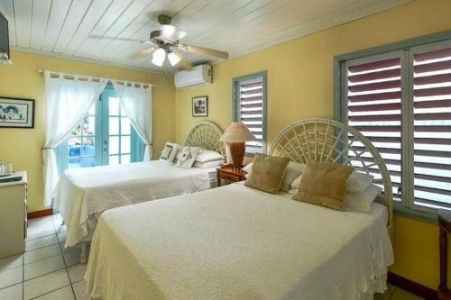 two beds in a room with yellow walls and windows at Titi Vacation Homes in Cobbs Cross