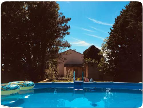 une grande piscine bleue avec une maison en arrière-plan dans l'établissement Studio Mas de Papé Verquieres Saint Rémy de Provence, à Verquières