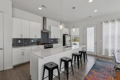 a kitchen with white cabinets and a large island with stools at PoolTable-15 Mins to Uptown & DT-King Bed! in Charlotte