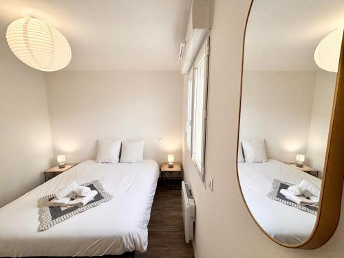 deux lits dans une chambre avec un miroir dans l'établissement L'Éclatant, Lumineux, Centre-ville, à Royan