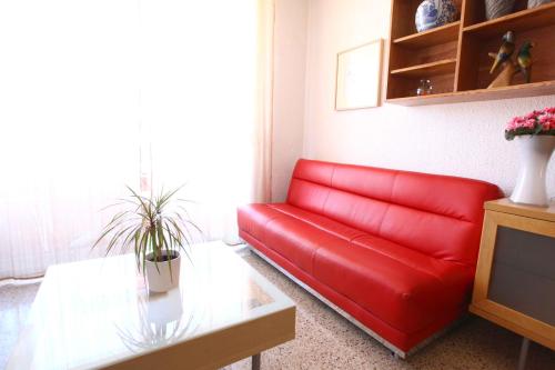 um sofá vermelho numa sala de estar com uma mesa em Bordeta em Barcelona