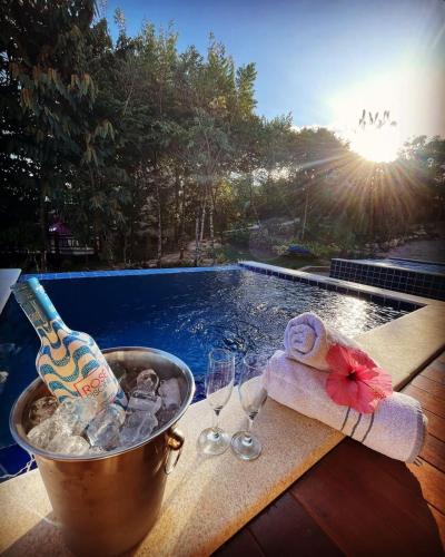 a bucket of champagne and wine glasses next to a swimming pool at Villa Tereza in Alto Paraíso de Goiás