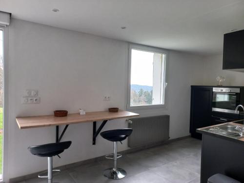 a kitchen with a counter and two stools in a room at GITE LA HOUBETTE VUE MAGNIFIQUE - Nature in Dommartin-lès-Remiremont