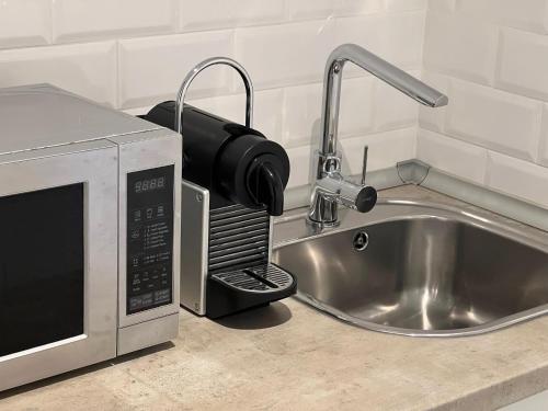 a kitchen counter with a sink next to a microwave at Constância Guest House in Constância