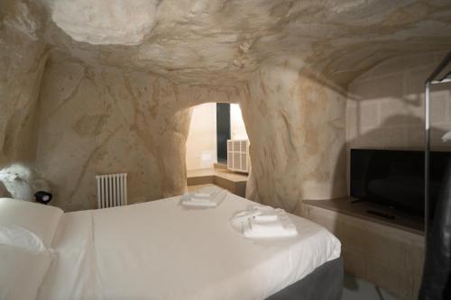 a bedroom with a white bed and a tv at Al Vico Affittacamere in Matera