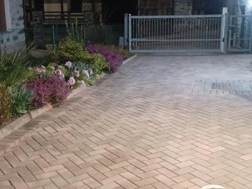 a brick driveway with flowers in a garden at B & B SENTIERO VALTELLINA in Castello dellʼAcqua