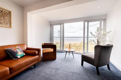 a living room with a brown leather couch and a table at Magnificent Beach House in Caister-on-Sea