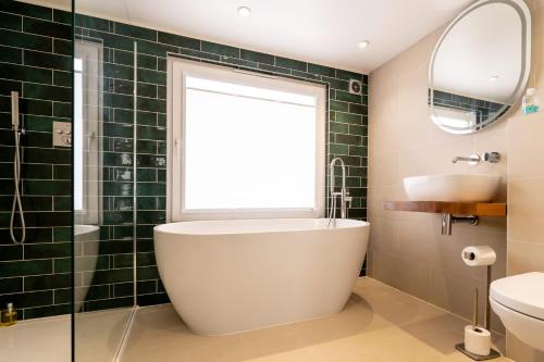 a bathroom with a tub and a sink and a window at Magnificent Beach House in Caister-on-Sea