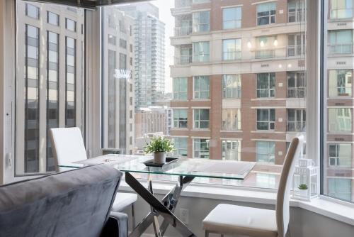 a table and chairs in a room with a large window at Discounted Elegant Yorkville Suite in Toronto