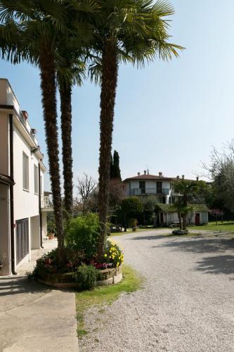 a street with palm trees and flowers in a driveway at Hotel Olimpia in Sirmione