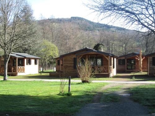 un groupe de cottages avec des arbres et des montagnes en arrière-plan dans l'établissement Camping de masevaux, à Masevaux