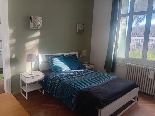 une chambre avec un lit avec des draps bleus et une fenêtre dans l'établissement Grande chambre cosy avec salle de bain et WC privatif, à Montpellier