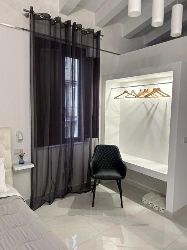a bedroom with a black chair in front of a window at B&B Il Sogno in Lamezia Terme