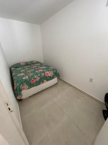 a small bedroom with a bed with a floral blanket at Barra de Jacuipe beach house in Barra de Jacuípe