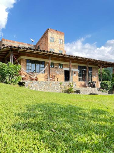 a large brick house with a grass field in front of it at El Cerrito Ventanas Parapente - Bed and Breakfast Premium in Piedechinche