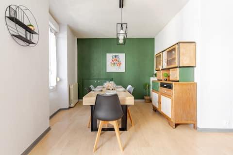 une salle à manger avec une table et un mur vert dans l'établissement MAISON DE VILLE AVEC GARAGE ET TERRASSE, à Lourdes