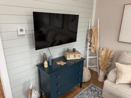 a living room with a blue dresser with a television on a wall at Jelly Bay in Bolivar Peninsula