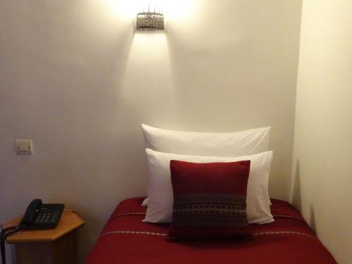 a bed with a red and white pillow and a phone at Riad Sabah in Fès