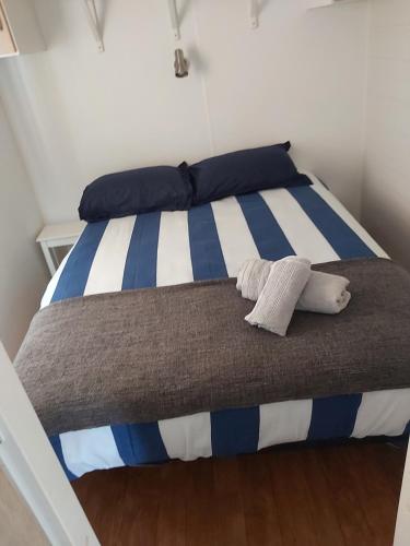 Elle comprend un grand lit avec des rayures bleues et blanches. dans l'établissement Bungalow tout confort, à Hourtin