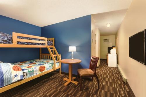 a bedroom with a bunk bed and a desk and a table at Days Inn by Wyndham Nanaimo in Nanaimo