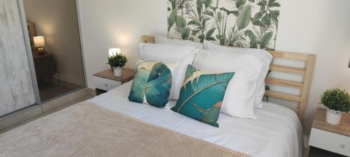 une chambre avec un lit avec des draps blancs et des oreillers dans l'établissement Appartement neuf à 100 m de la plage - New 100m from beach, à Fréjus