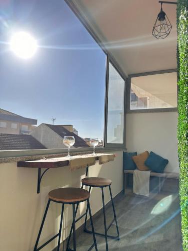 a kitchen with two stools and a bar with windows at Furadise Apartment in Ovar