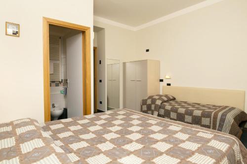 a bedroom with two beds and a bathroom at Hotel Olimpia in Sirmione