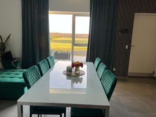 a white table with green chairs and a table with flowers on it at 3 km to Legoland in Billund