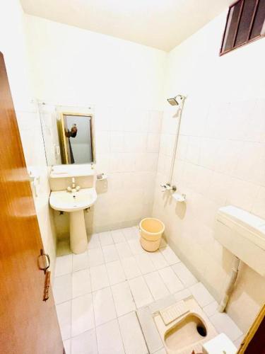 a white bathroom with a toilet and a sink at Citymax Hotel in Rawalpindi