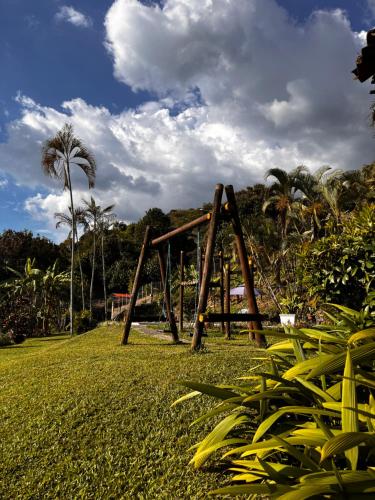 a wooden swing set in a field with palm trees at Santa Elena Ventanas Parapente Bed and Breakfast Premium in Santa Helena