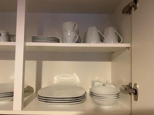a white cabinet filled with plates and dishes at Ferienwohnung Silvia in Villingen-Schwenningen