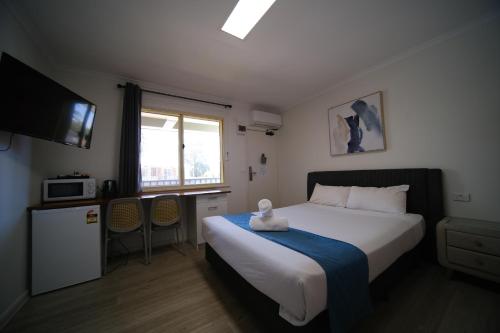 a bedroom with a bed and a kitchen with a microwave at Golf Place Inn Wollongong in Wollongong