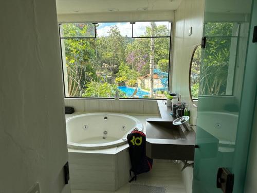 a bathroom with a tub and a sink and a window at Chácara Meu Pedaço Atibaia in Mairiporã