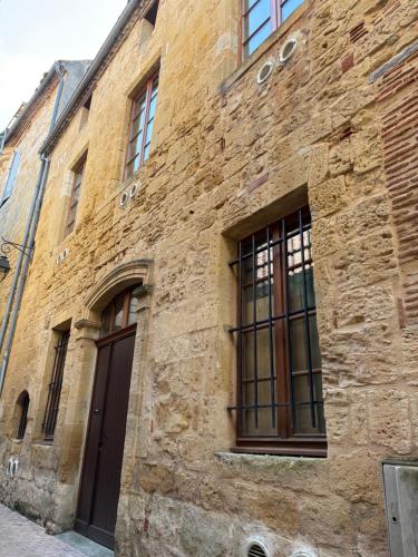 un ancien bâtiment en briques avec des fenêtres et une porte dans l'établissement Barrio Cyrano Appartement-Centre Historique, à Bergerac