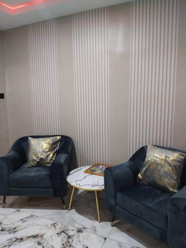 a living room with two blue couches and a table at Apartment In Rose Garden Ipaja in Ajegunle