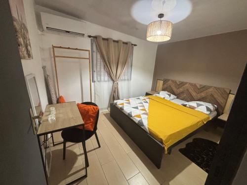 une chambre avec un lit jaune et une table dans l'établissement Lynn Lodge SLM, à Saint-Laurent du Maroni